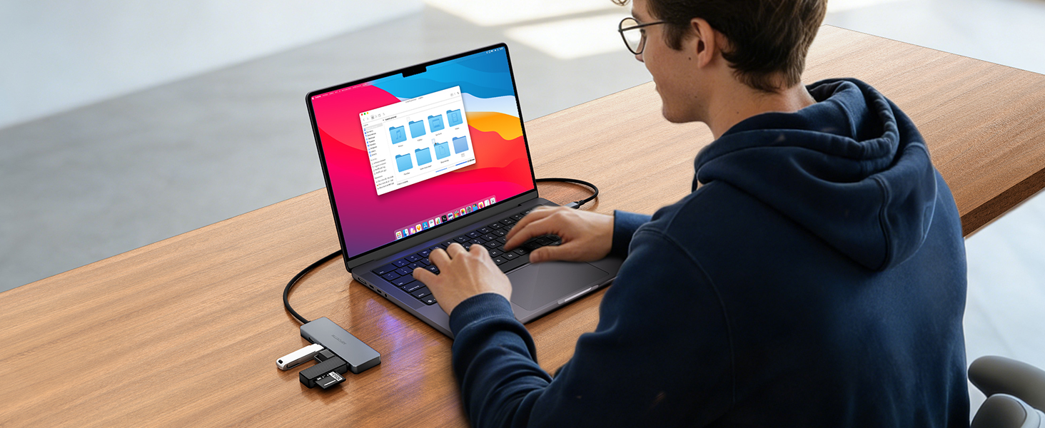 Person working on laptop showing colorful screen display, with smartphone visible on desk beside computer.