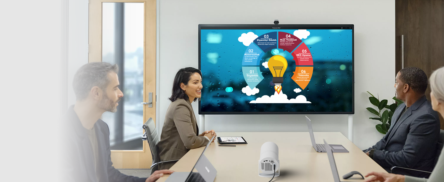 Business meeting scene with wall-mounted display showing colorful infographic wheel diagram, office setting with modern furnishings.