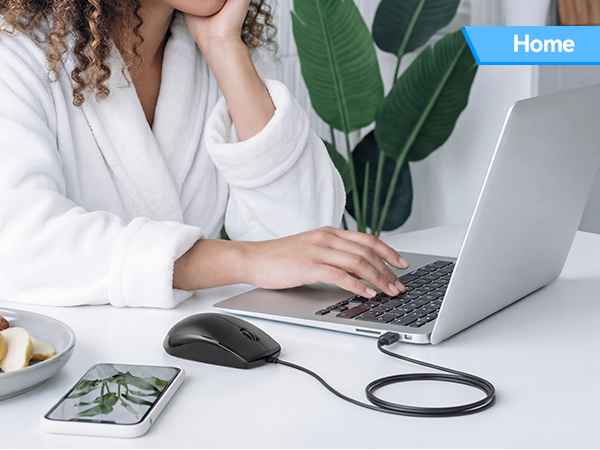 Text reads 'Home'. Woman at desk using laptop with mouse and keyboard visible on white surface.