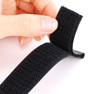 Close-up of a hand holding a strip of black hook-and-loop fastener, demonstrating its flexibility and texture.