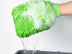 Green textured cleaning glove being demonstrated with water running over it, showing cleaning and water absorption capabilities.