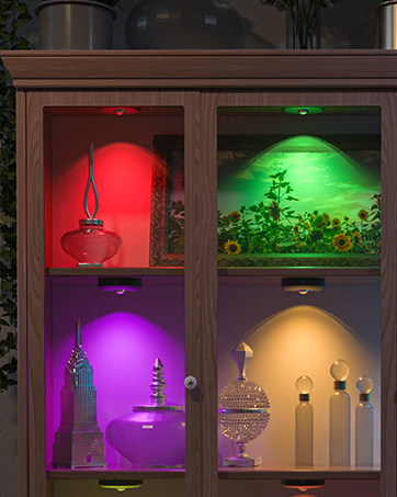 Display cabinet with four compartments illuminated in different colors: red, green, purple, and yellow. Each section contains decorative objects.