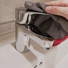 a person cleaning a sink with a cloth.