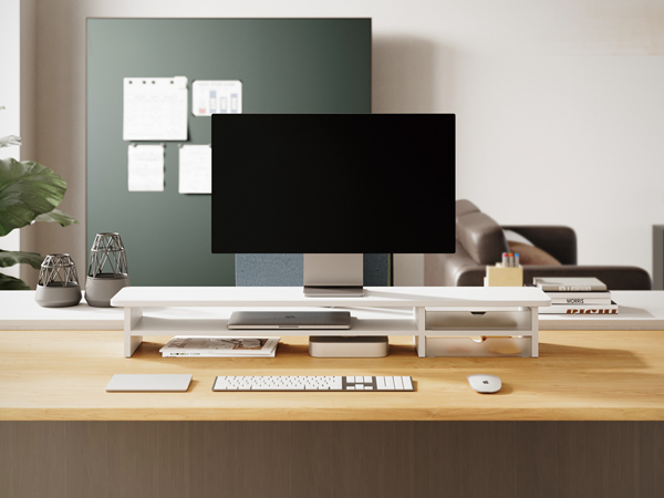 Modern home office setup with large monitor, wireless keyboard and mouse on a wooden desk. Green accent wall with white organizers in the background.