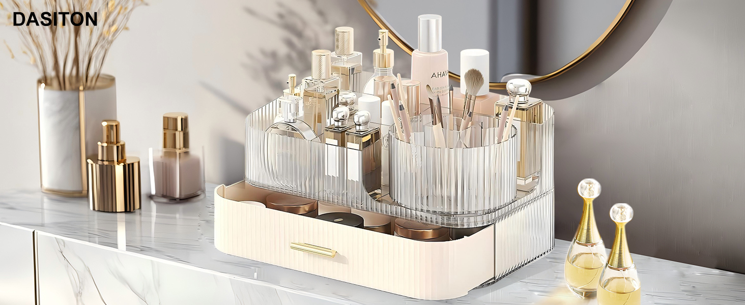 Clear acrylic cosmetic organizer with multiple compartments, holding various makeup and skincare products. Beige base section with drawer. Displayed on marble countertop with decorative items.
