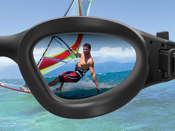 Black-framed sunglasses lens reflecting a windsurfer in action on blue water, demonstrating the clarity and field of view of the eyewear.