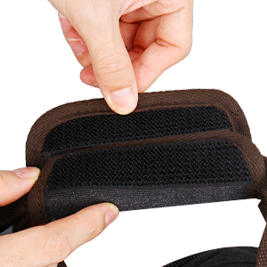Hands demonstrating the adjustable hook-and-loop closure on a black fabric orthopedic or supportive strap, showcasing its flexibility and customizable fit.