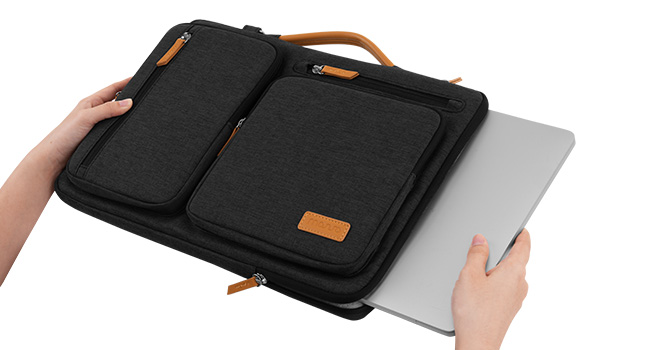 Hands holding black fabric storage bag with brown leather handles and corner accents, displayed over white background.