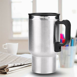 Stainless steel travel mug with a black handle, shown on a desk with office supplies in the background.