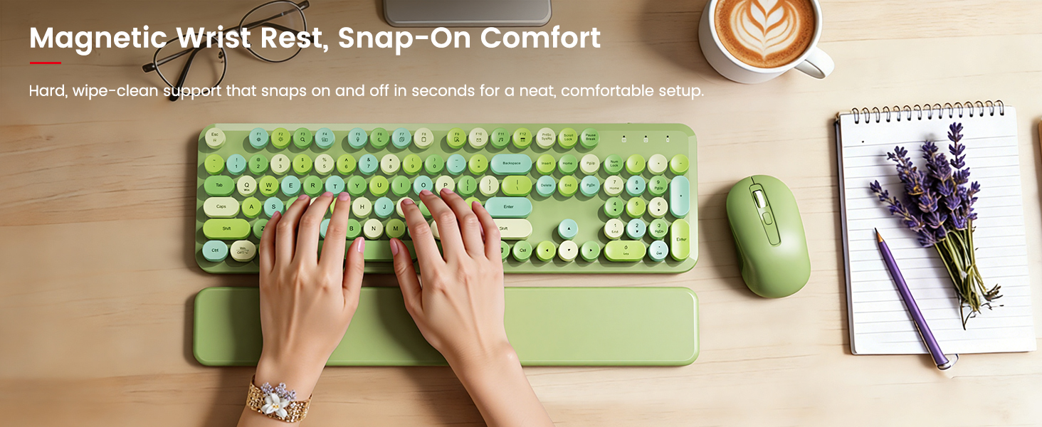 Hands typing on green keyboard with magnetic wrist rest and mouse on wooden desk