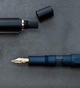 Close-up of a navy blue fountain pen with gold accents against dark background. Pen cap visible separately.
