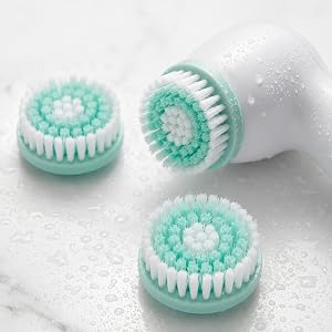 Conair True Glow facial brush unit resting on marble with extra brush heads