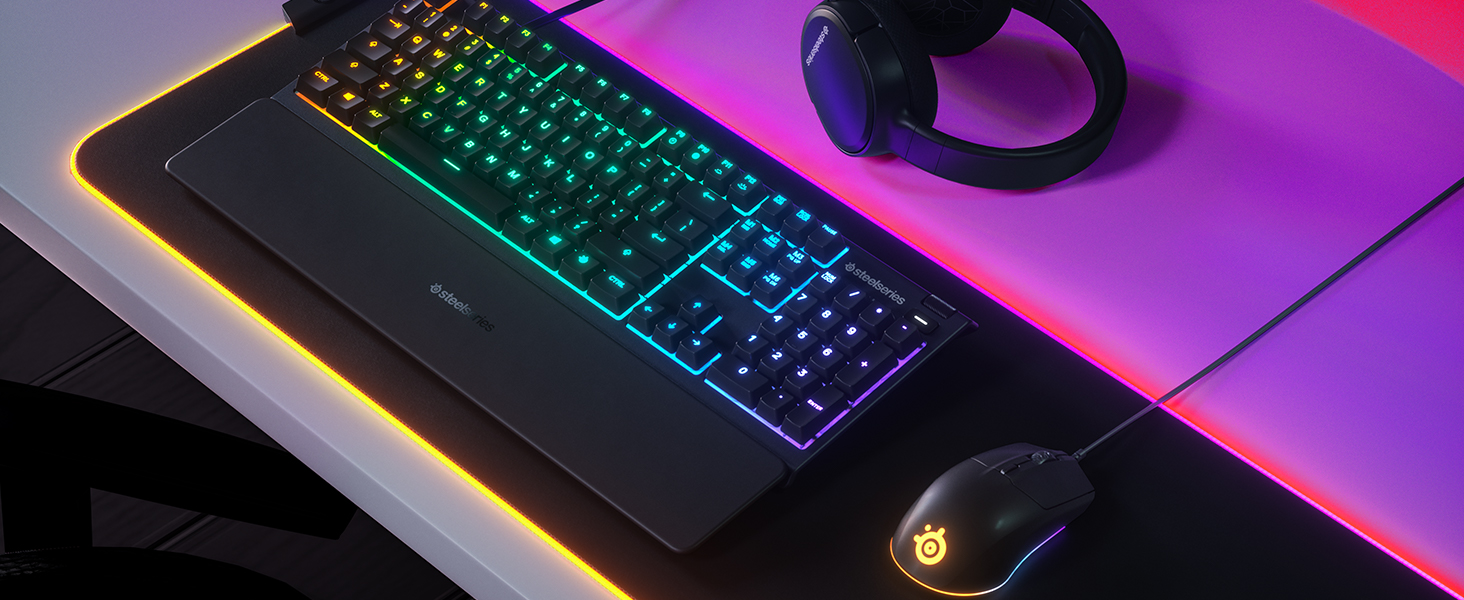 - A SteelSeries desk setup including Apex keyboard, Arctis headset, and Rival 3 mouse