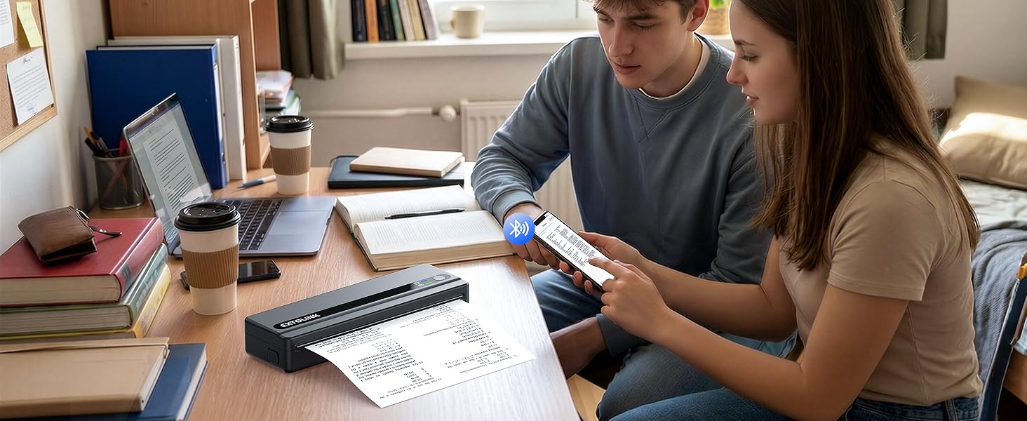 Two people seated at desk reviewing documents and looking at mobile device together in study or work setting