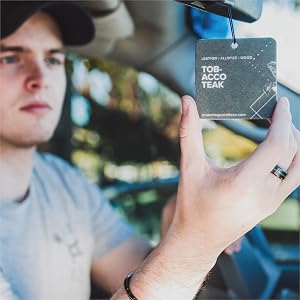 man in car hanging tobacco teak car freshener