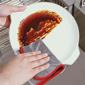 a person cleaning a dish with a towel.