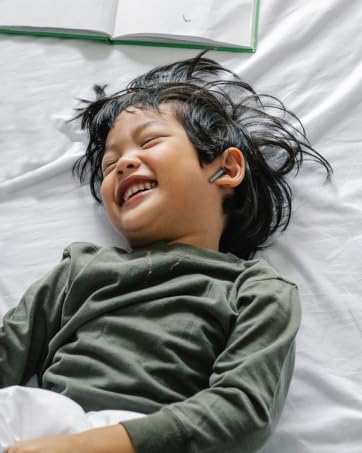 a child is lying on a bed with a book and a pen.