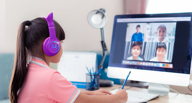 Purple over-ear headphones worn by a person using a computer for video conferencing, showing multiple participants on screen.