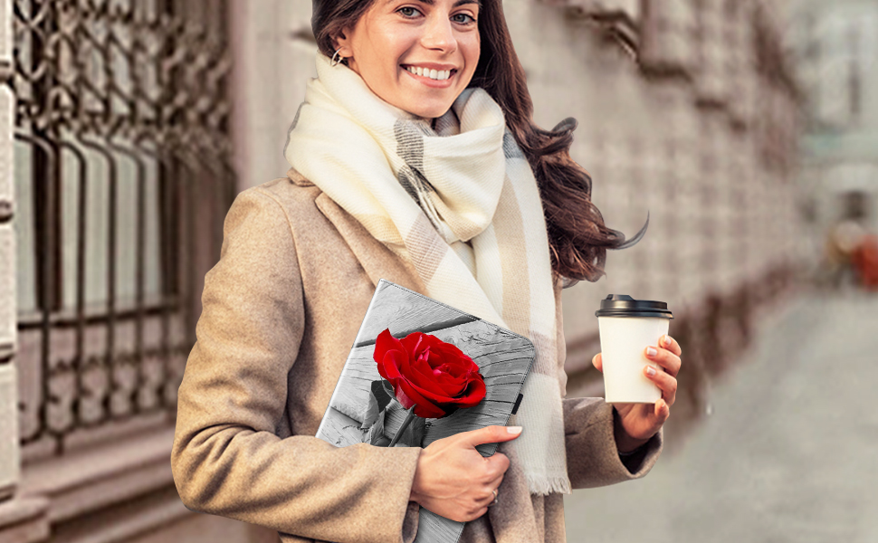 Woman in beige coat and white scarf outdoors, holding a red rose and coffee cup. She is smiling and has long dark hair.