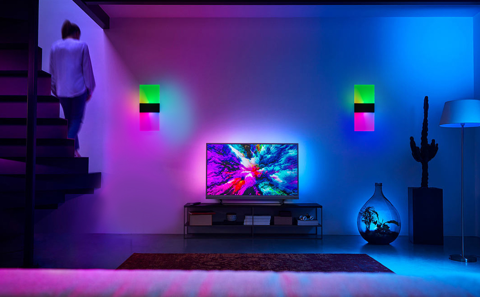Gaming room setup with TV mounted on wall, illuminated by purple and blue LED ambient lighting with wall-mounted light cubes.