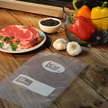 LEM vacuum sealer bag surrounded by meat, garlic, peppers, and spices