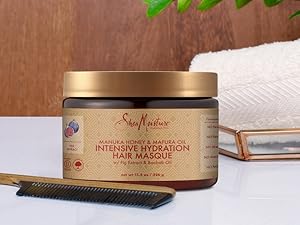 Hair Masque container on white surface with comb and towel, set against a wooden background.