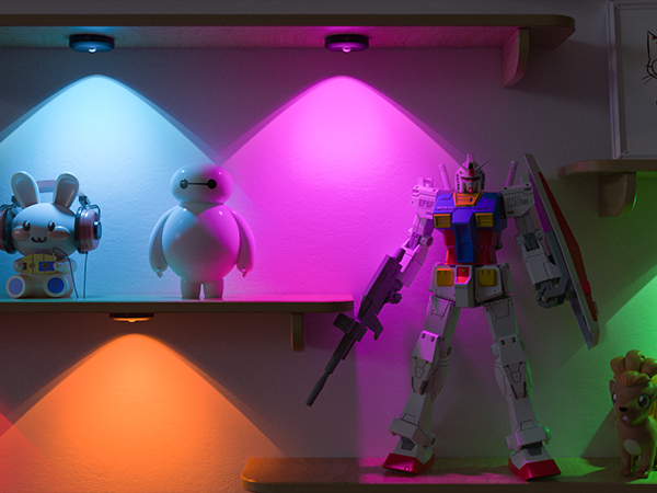 Colorful LED lights demonstrating different hues - blue, pink, orange, and green. Toy figures and a model robot visible in the illuminated areas.