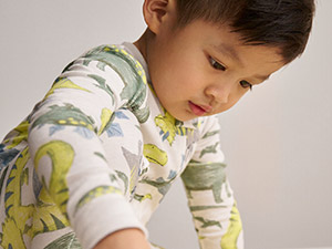 toddler boy wearing dinosaur print pajamas