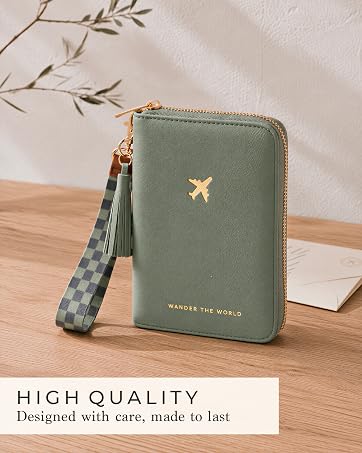 Sage green travel wallet with gold details and wrist strap, styled on a wooden table
