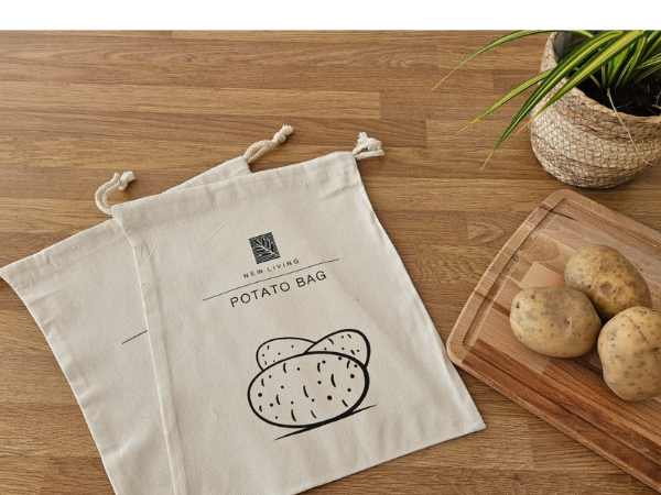 Text reads 'POTATO BAGS' with potato illustration. Two cream canvas drawstring storage bags displayed on wooden surface with fresh potatoes.