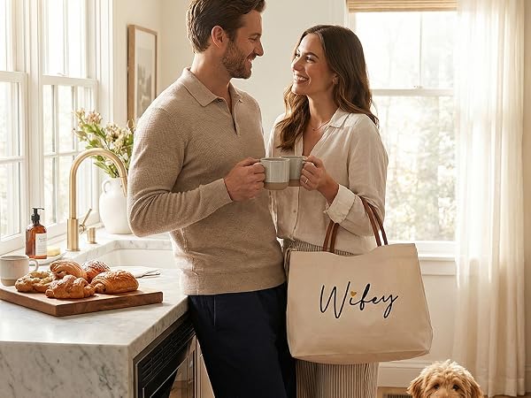A couple in a kitchen with the woman carrying a Wifey canvas tote bag during a coffee morning.