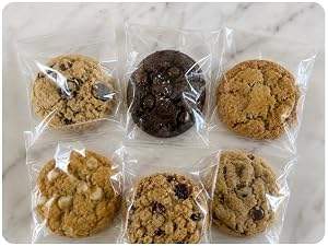 Six assorted cookies individually wrapped in clear Pack It Chic cello bags on a marble counter