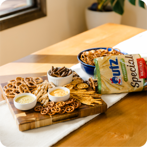 Utz Sourdough Special Pretzels on a wooden board with dips and a cozy dining backdrop.