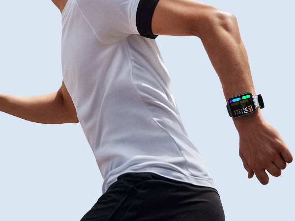 Person wearing a white t-shirt and black shorts running, with a digital fitness watch visible on their left wrist.