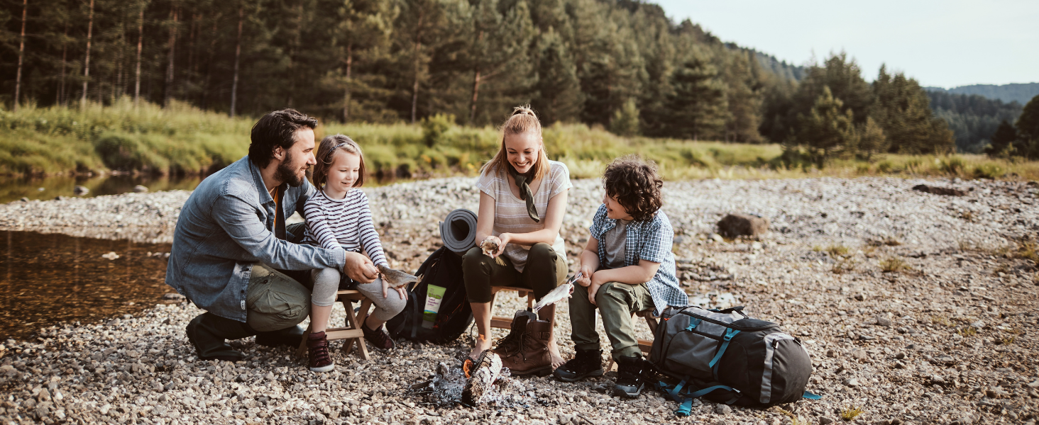 family happily sitting around a camp fire out in the wilderness
