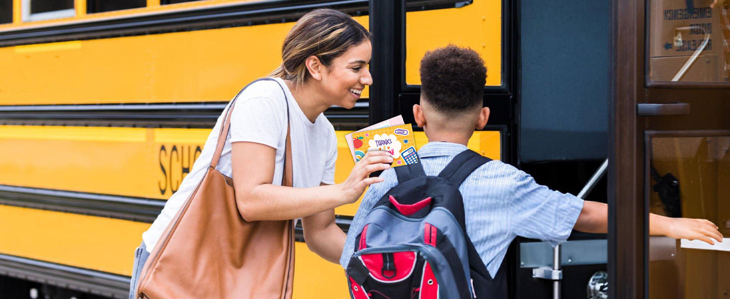 A boy is giving her teacher a teacher appreciation greeting card to make her feel appreciated.
