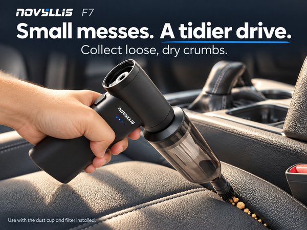 Handheld car vacuum collecting loose dry crumbs from a leather seat seam with a brush nozzle