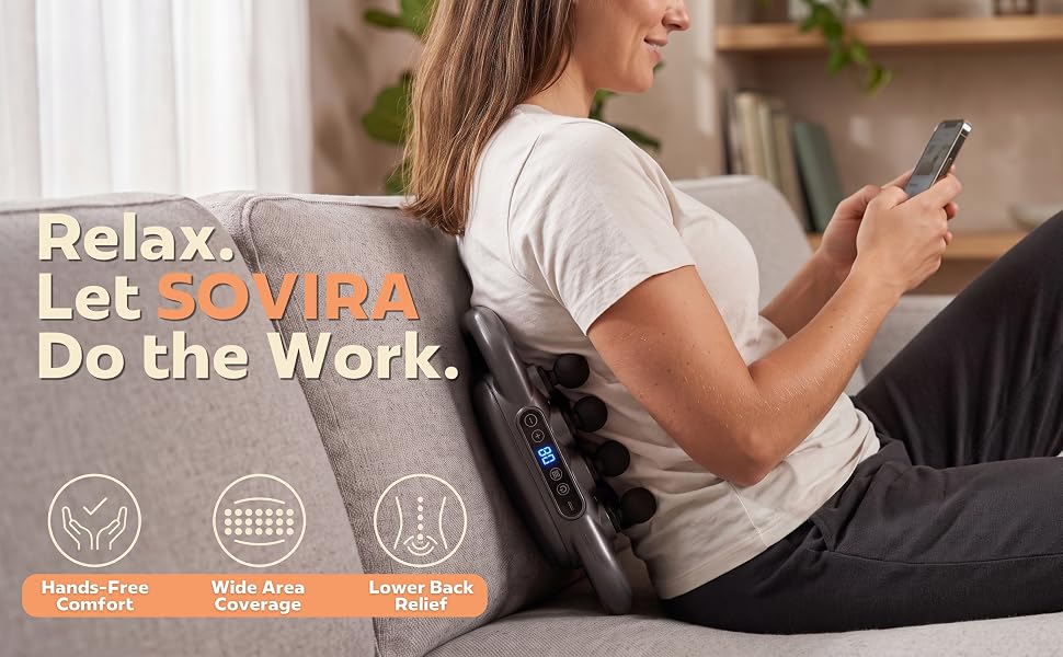 Woman using the SOVIRA massager on her lower back while relaxing on a sofa.