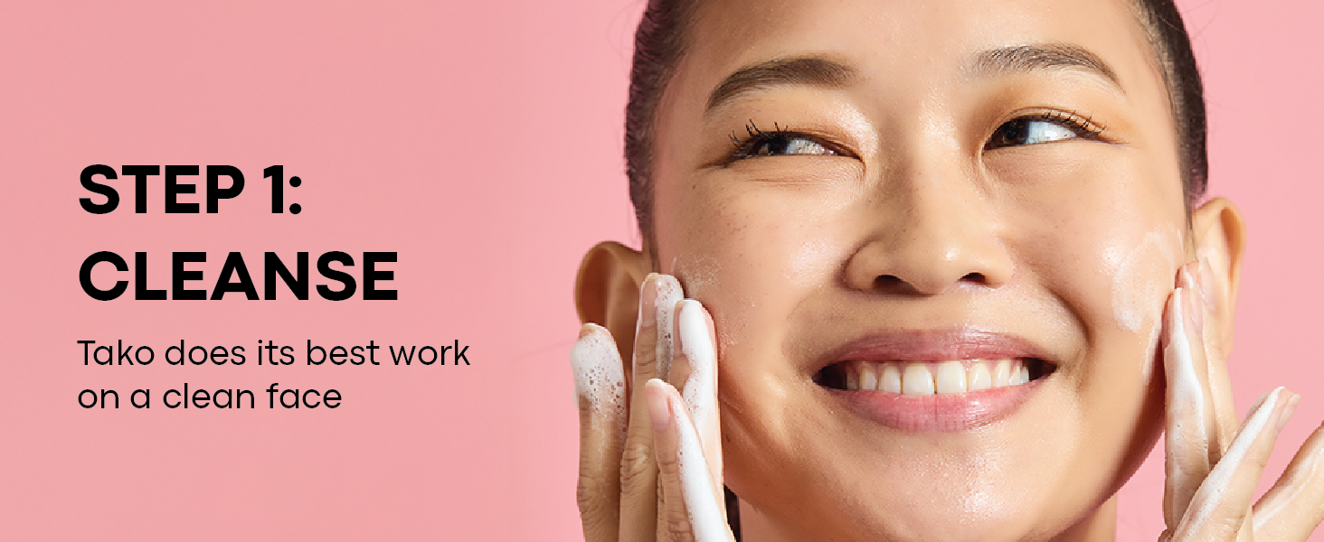 Step 1 - Cleanse: smiling model washing face with foamy cleanser on a pink background