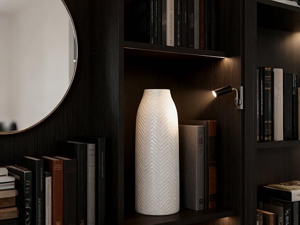In a dark wood multi-layer bookshelf scene, a white ceramic vase with herringbone texture