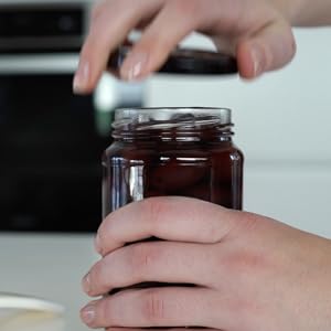 Person taking off the lid of a jar after using JarKey