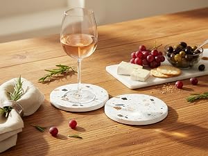 Terrazzo coaster set with wine glass and fruits on rustic wooden dining table