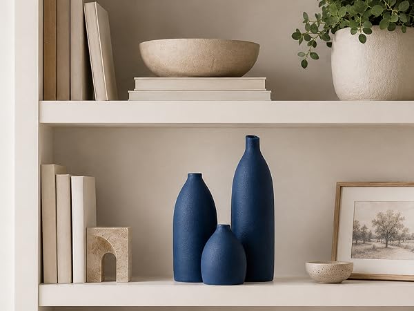 Deep navy ceramic vases styled on a neutral bookshelf with modern home decor.