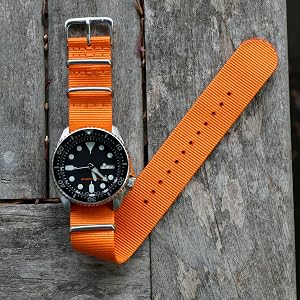 Orange Nylon Watch Band on Black Dive Watch against Wood Background