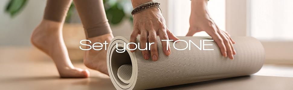 woman rolling up a yoga mat in home workout studio with text set your tone