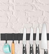 Kitchen knife set with four stainless steel blades of varying sizes, displayed on a black magnetic strip with colorful utensils hanging below.