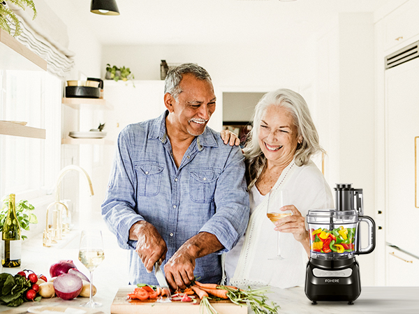 a couple cutting vegetables in a kitchen