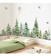 Children's bedroom with watercolor-style forest wall mural featuring pine trees, birds, and woodland elements. Green bedding and natural wooden toys visible.