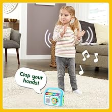 Player makes music and says: Clap your hands! Kid dances and claps her hands with music player.