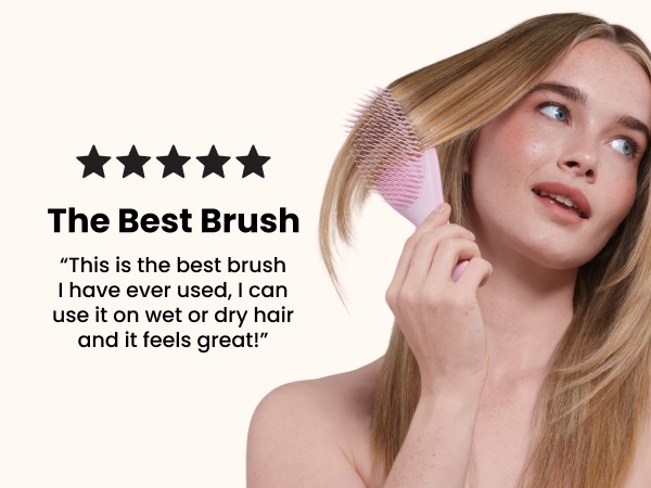 A woman brushing her hair with a pink ultimate detangler brush.